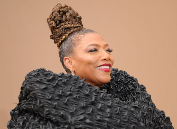 Queen Latifah smiling in a textured black coat